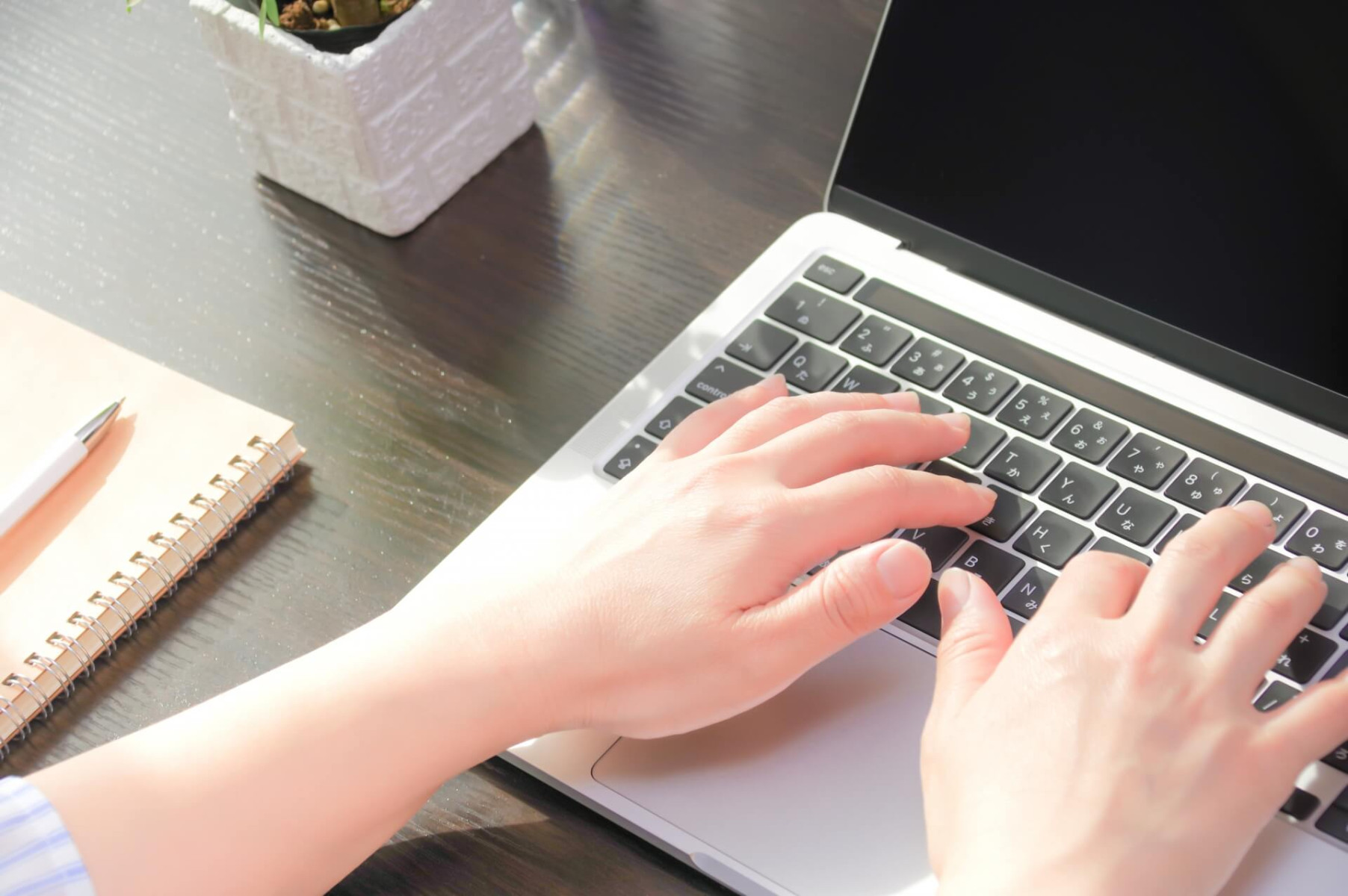 デスクでノートパソコンを操作する手