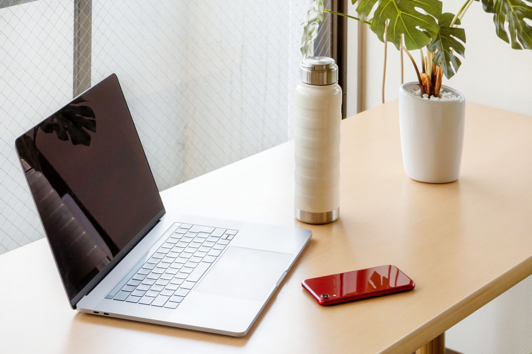 明るい部屋のデスクに置かれたノートパソコン